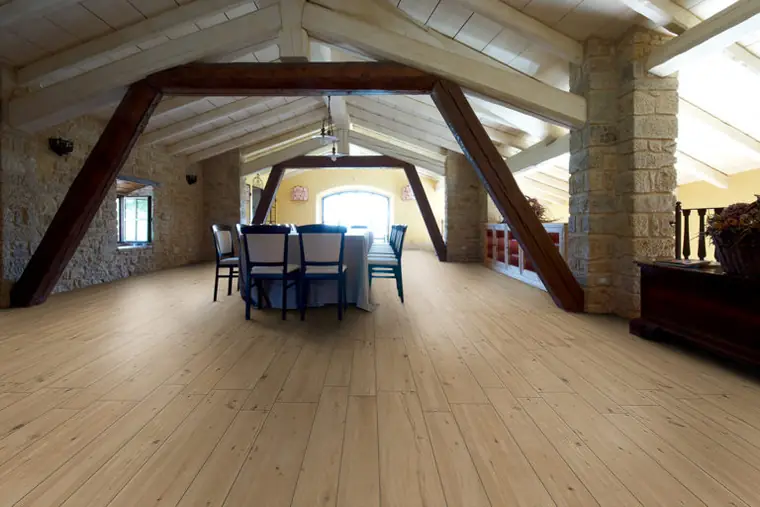 Mansarda con travi a vista e pavimento effetto legno chiaro
